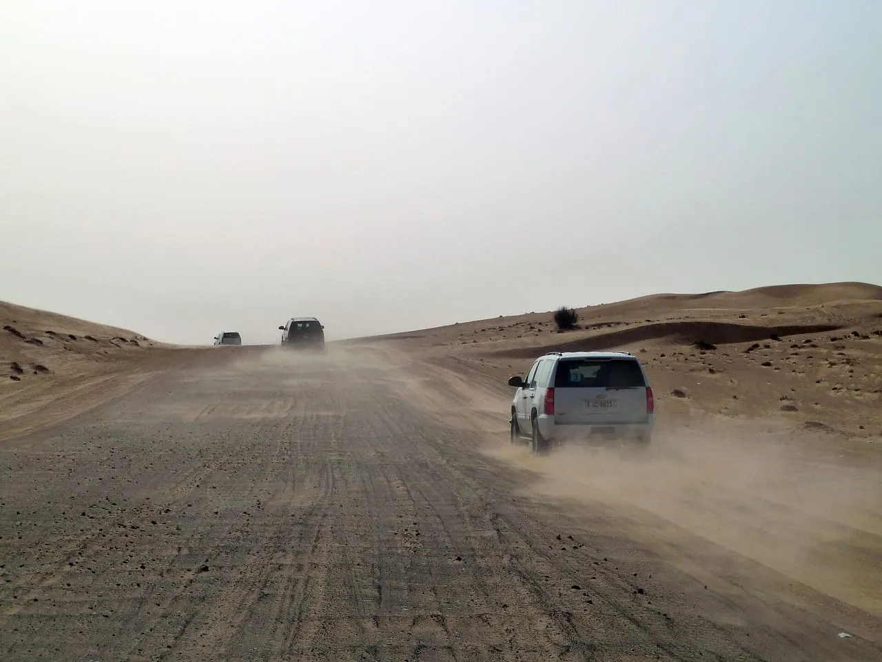 Safari 4x4s driving in convoy along a sandy track through the Al Marmoum desert south of Dubai
