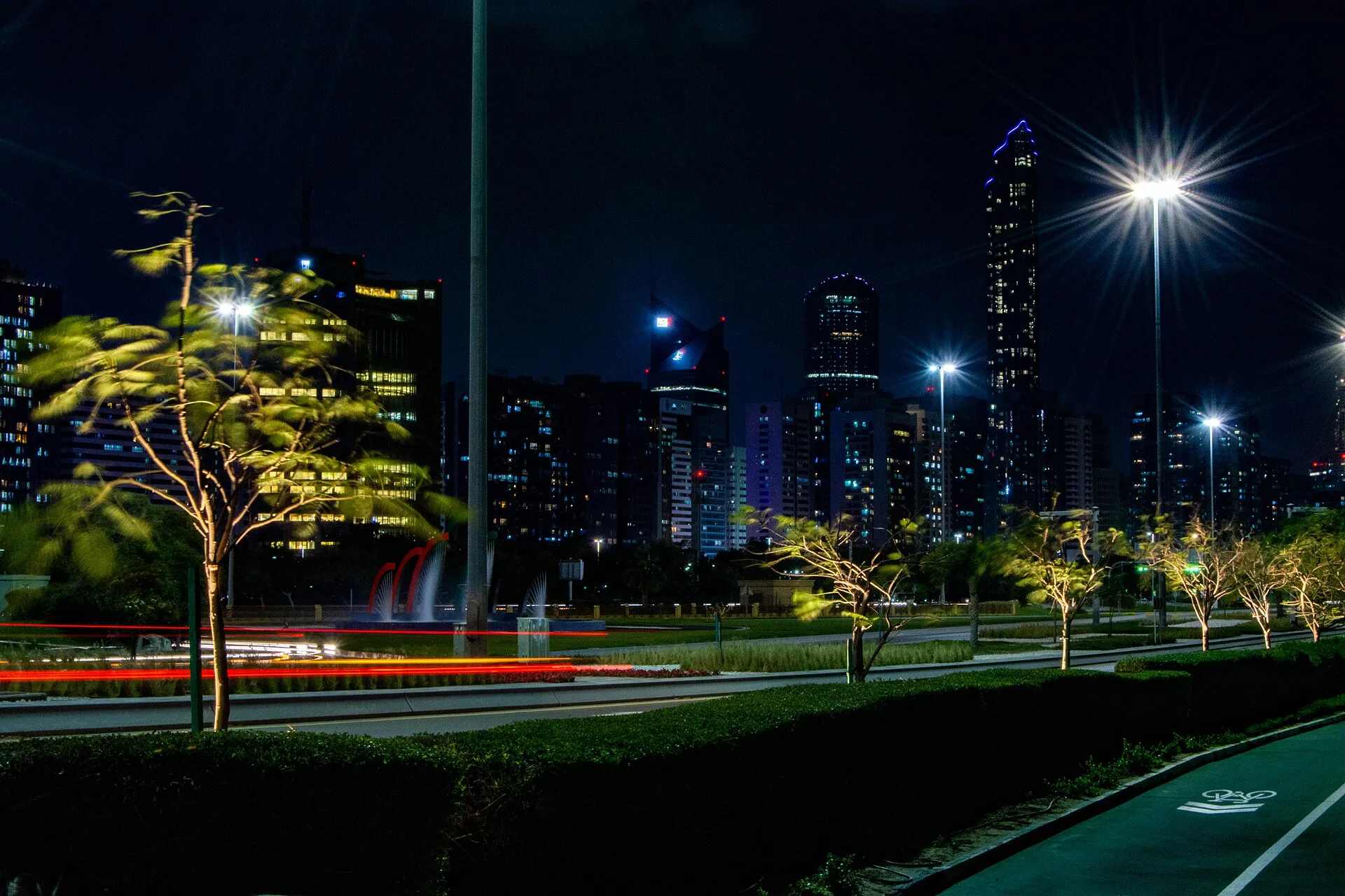 Abu Dhabi towers lit up at night with a trail of car lights in front