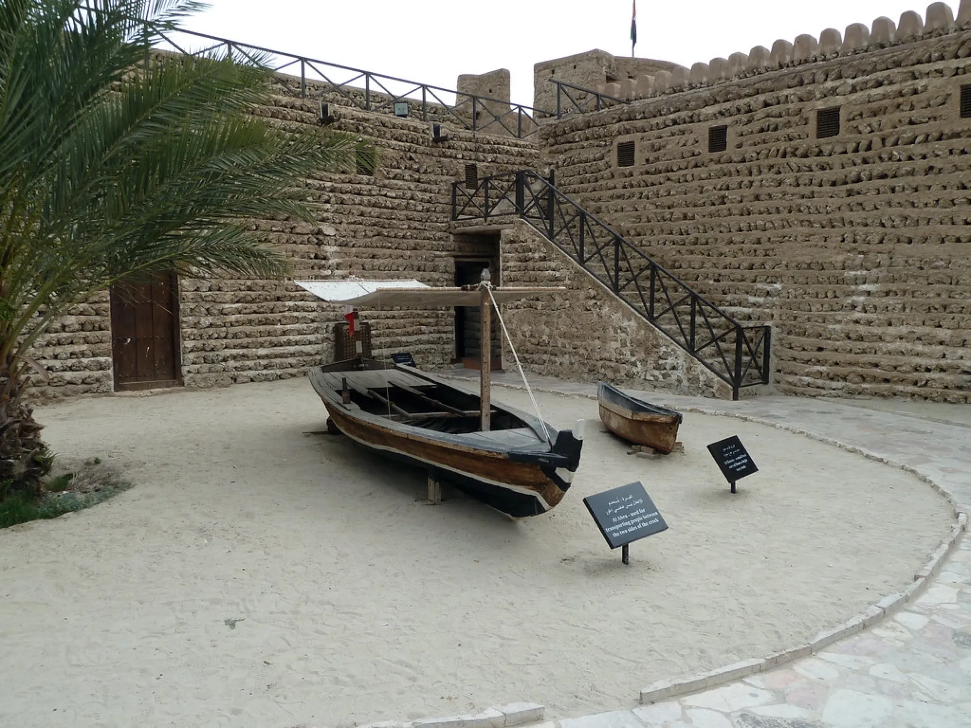 A wooden abra boat on display in the sand courtyard of Al Fahidi Fort, home of the Dubai Museum