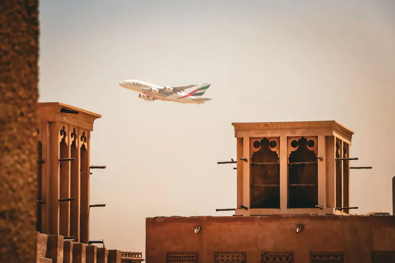 Wind towers in the Al Fahidi historical district of old Dubai with an aircraft overhead