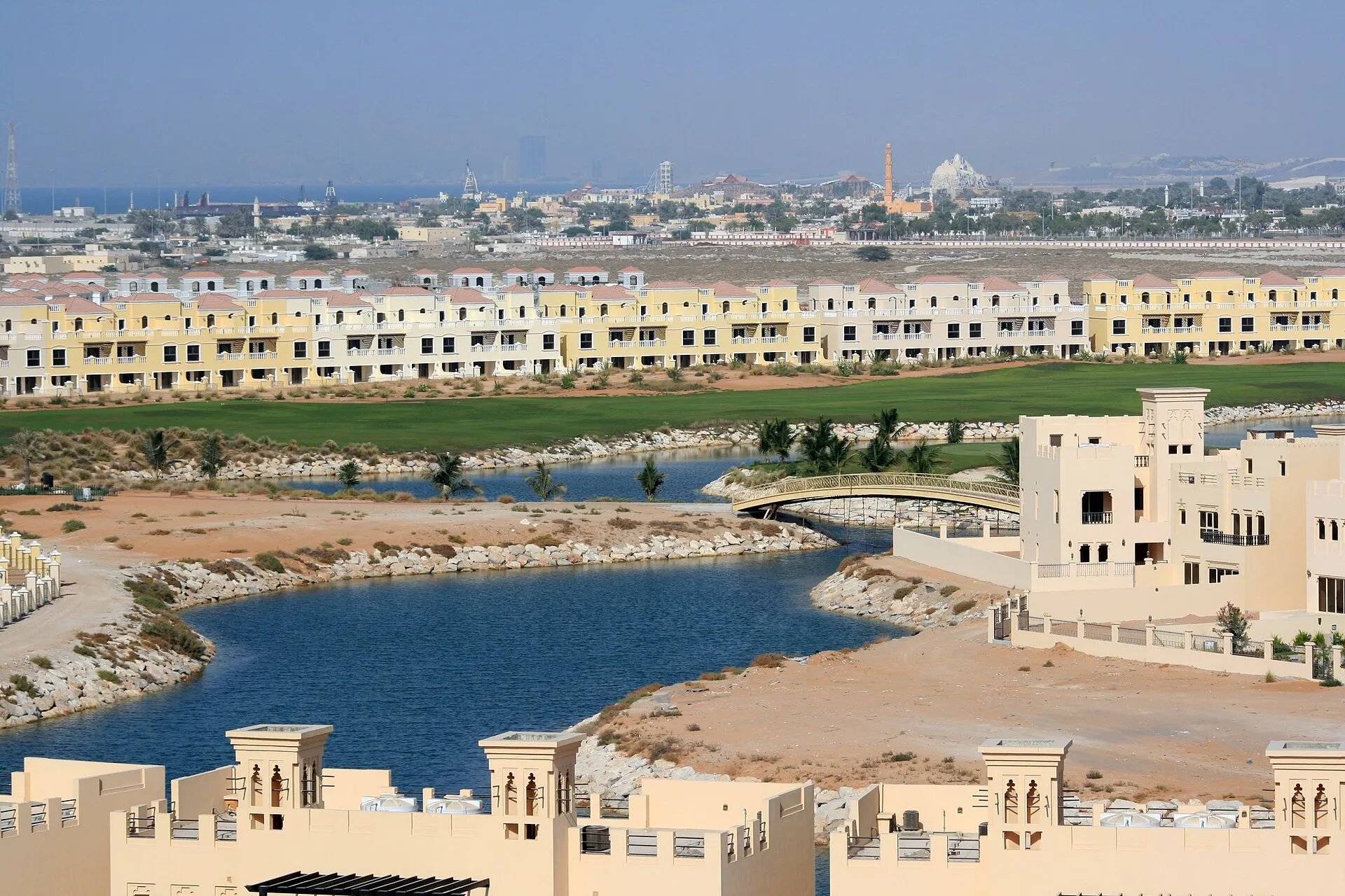 Sand-coloured villas, a lagoon and a footbridge at Al Hamra Village in Ras Al Khaimah