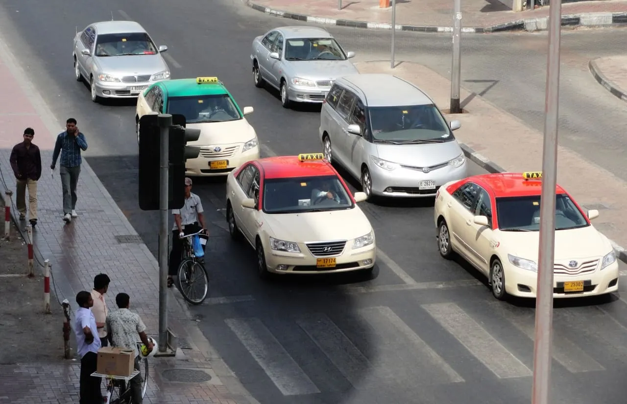 Red-roof and green-roof taxis stopped at a pedestrian crossing in Bur Dubai