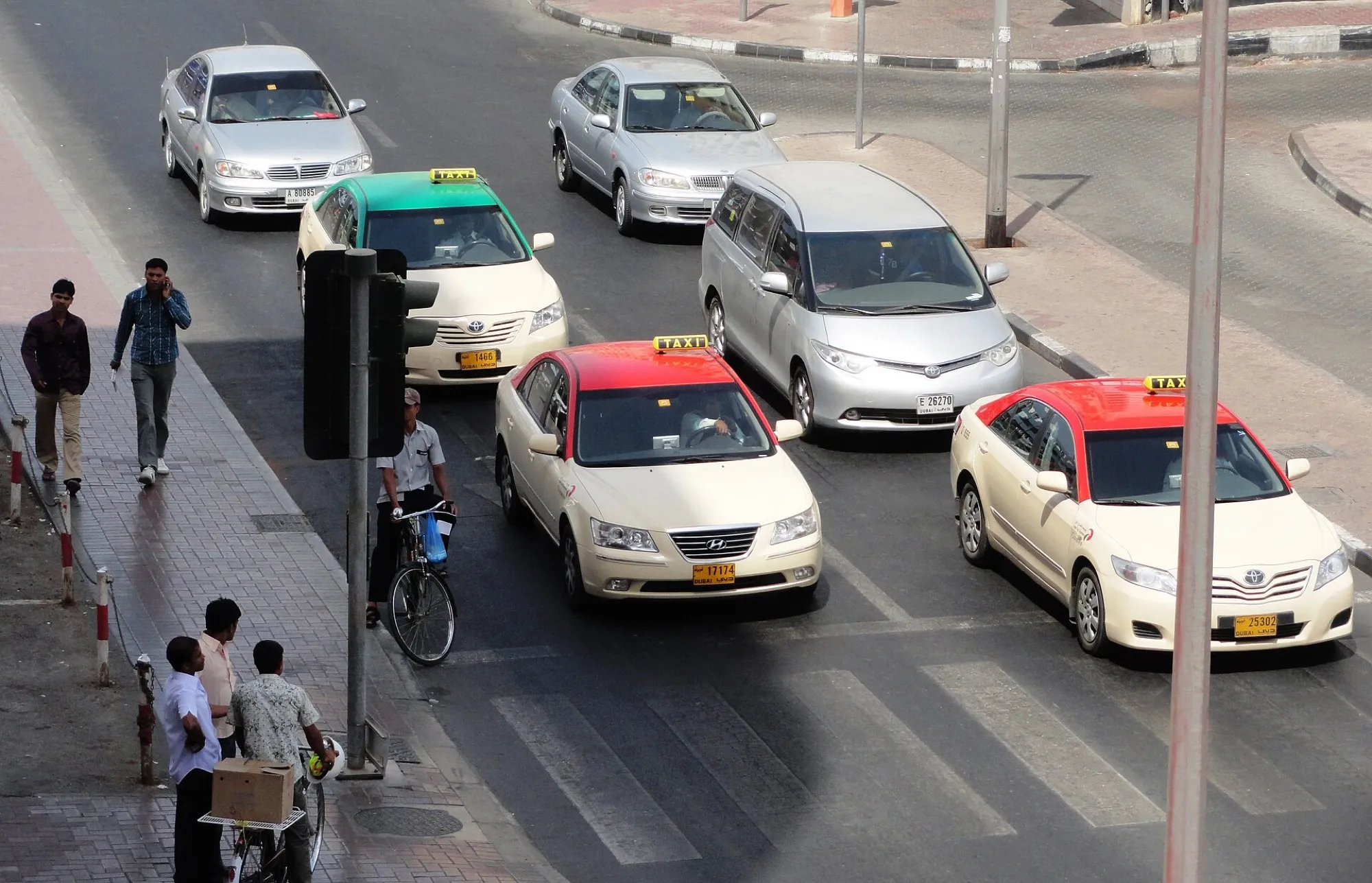 Licensed Dubai taxis in red and green roof colours at a junction in Bur Dubai