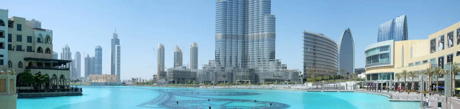 Panorama of the Burj Khalifa rising above the Dubai Fountain lake, with Dubai Mall on the right