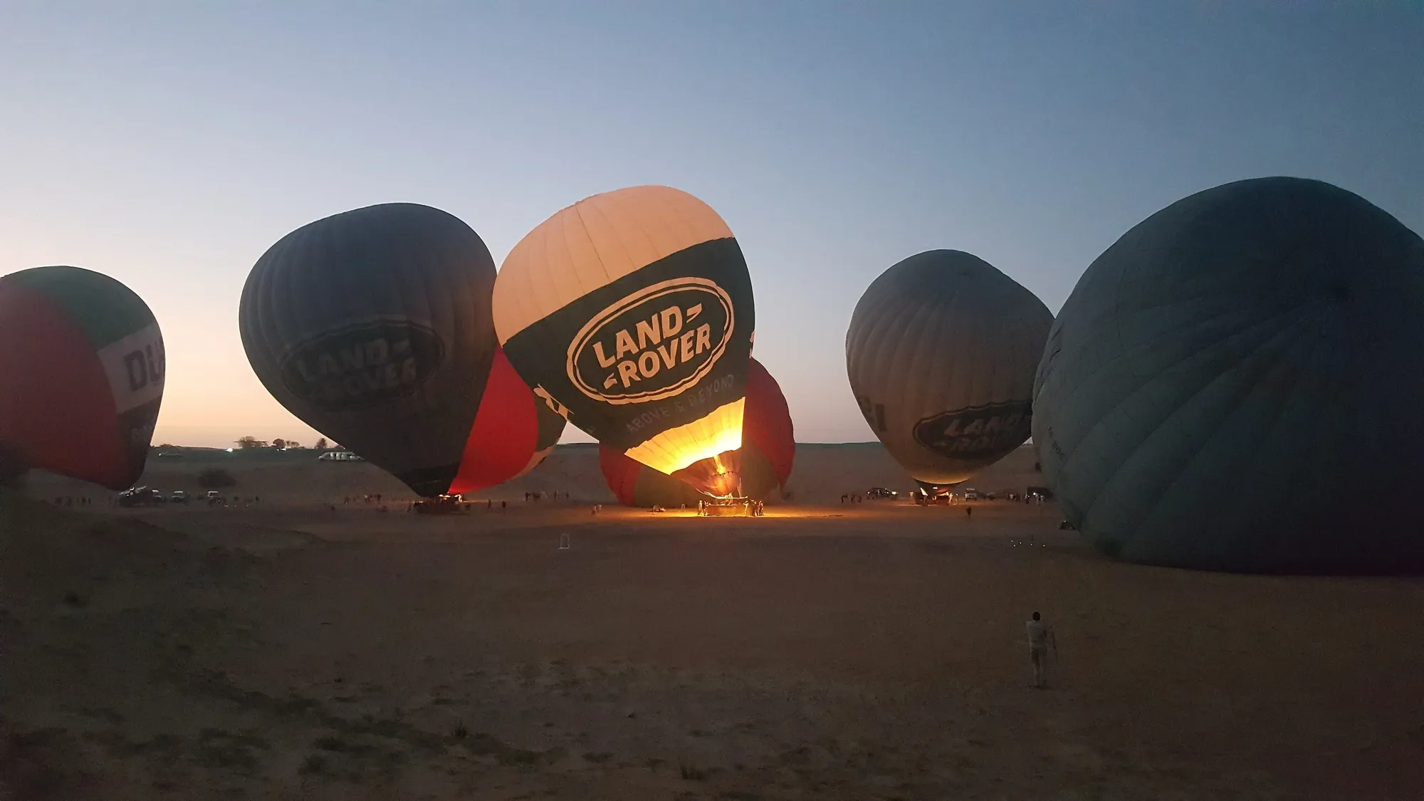 Burners heating the envelopes of hot air balloons at a desert take-off site near Dubai at dawn