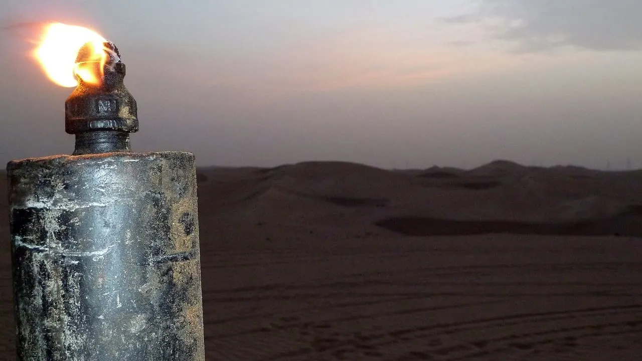 A lit torch on a post at dusk, looking out over the dunes of the Al Marmoum desert in Dubai