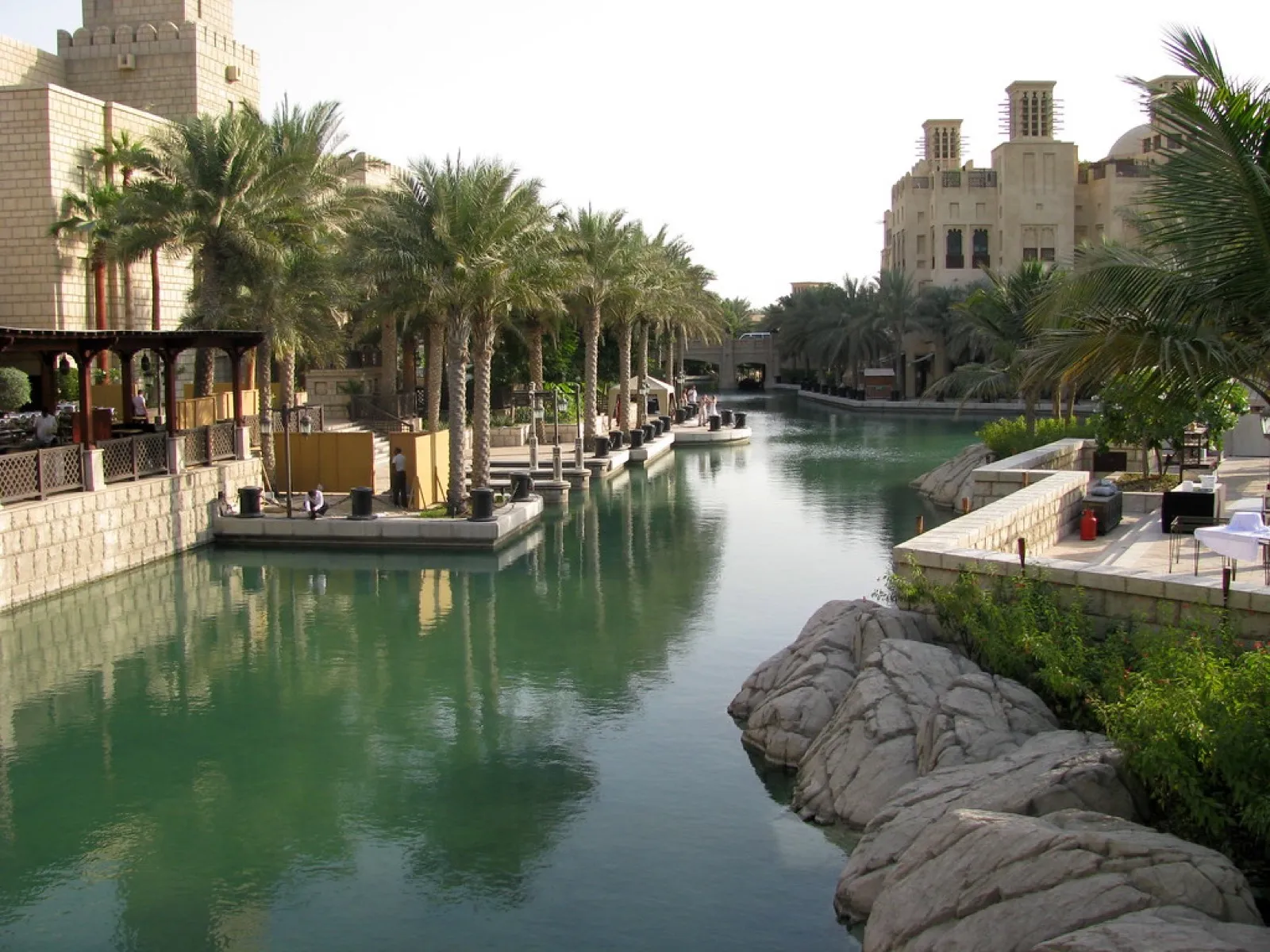 A palm-lined canal at Madinat Jumeirah with wind-tower buildings and landing stages along the water