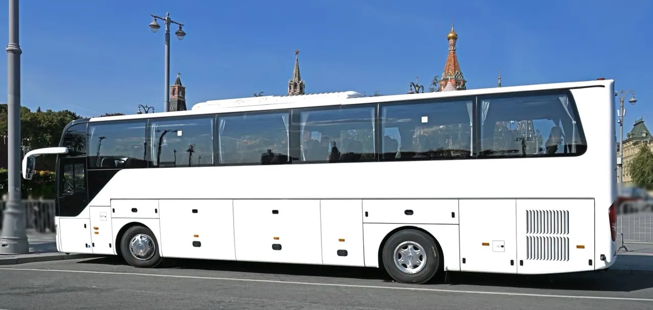 Side view of a white full-size tour coach, a representative image of the 50-seat coach; the partner's coach may differ