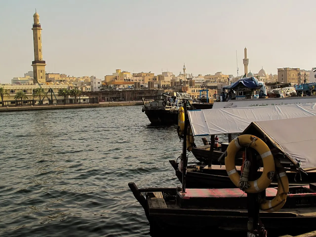 Abras moored on Dubai Creek, looking across the water to the minarets and low buildings of Bur Dubai