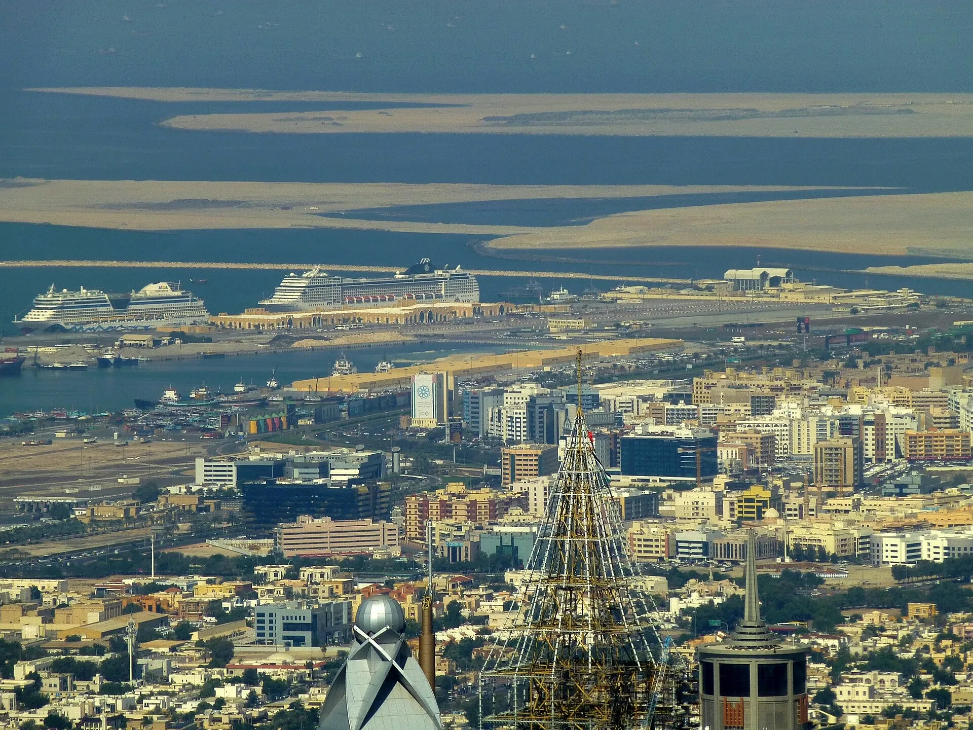 Two cruise ships berthed at Mina Rashid, seen from the Burj Khalifa across the rooftops of Dubai