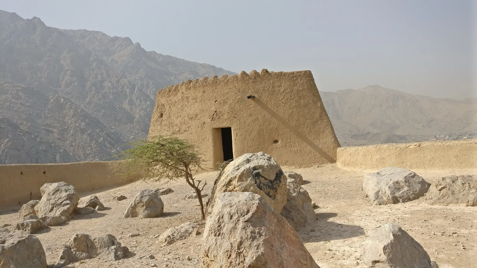The mud-brick tower of Dhayah Fort on its hilltop, with the Hajar mountains behind
