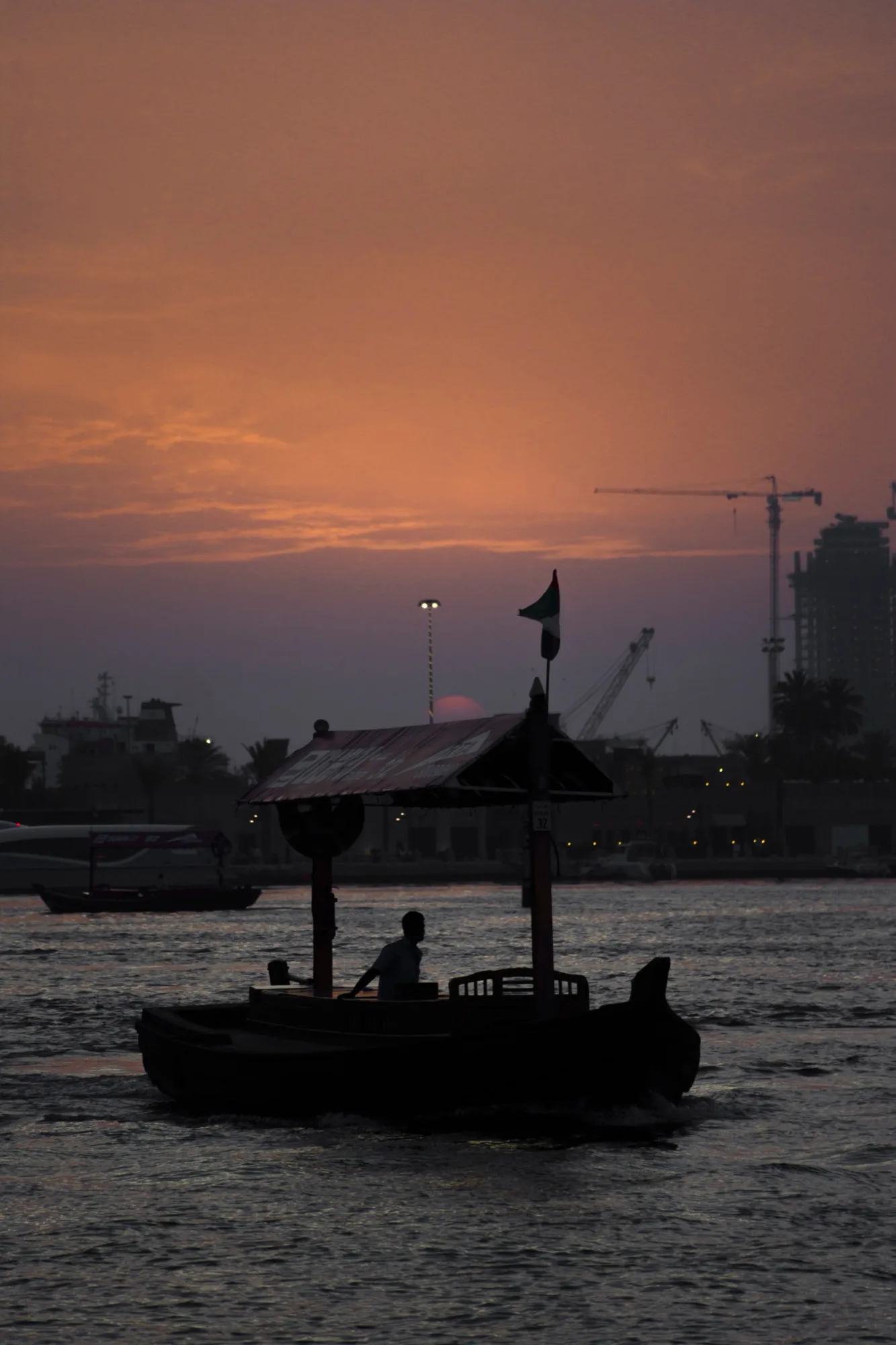 A traditional abra water taxi crossing Dubai Creek at sunset