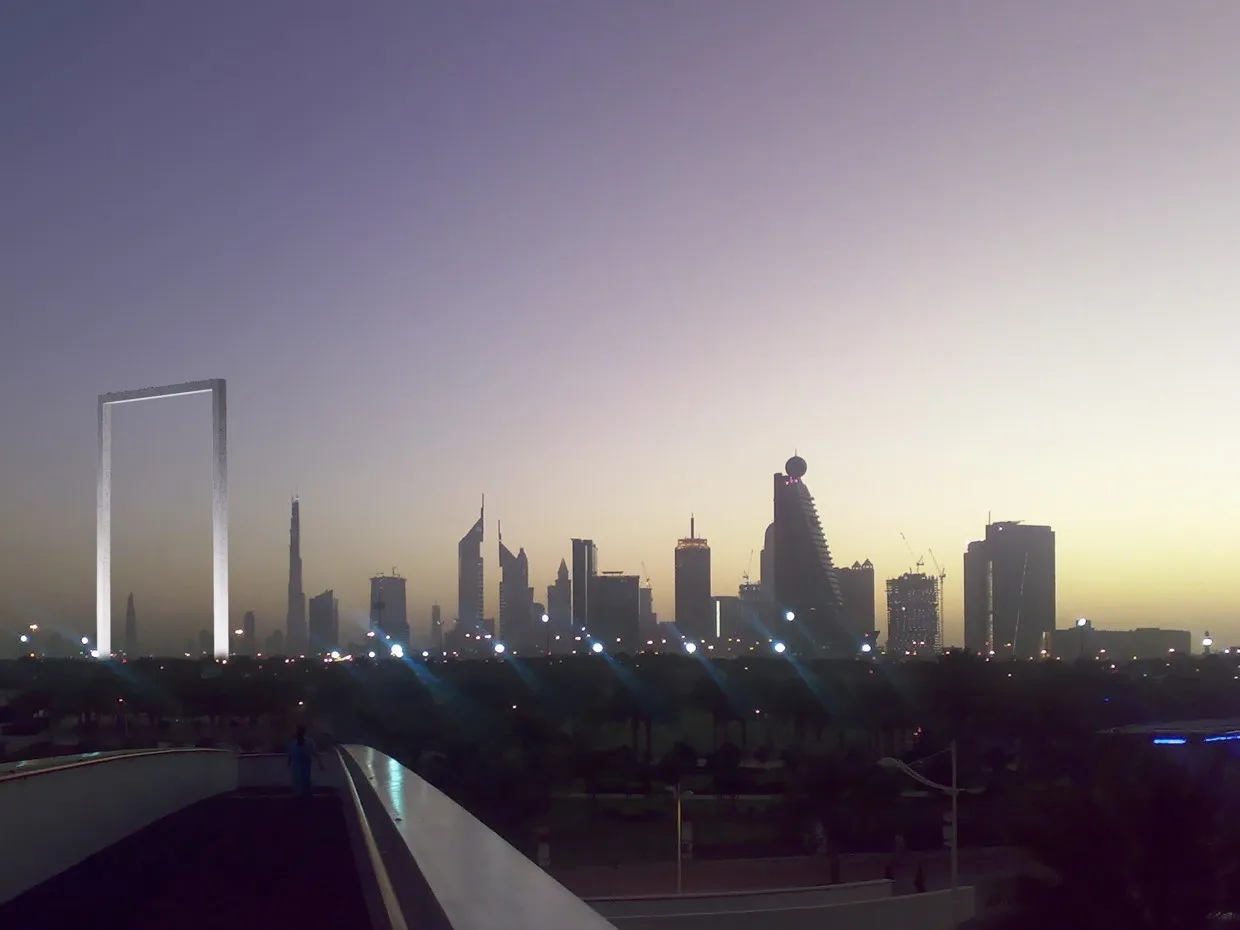The Dubai Frame in Zabeel Park lit up at dusk, with the city skyline behind