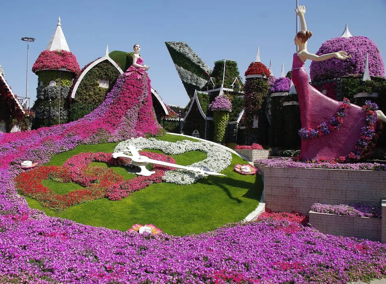 Flower-covered figures, cottages and a floral clock at Dubai Miracle Garden under a clear sky