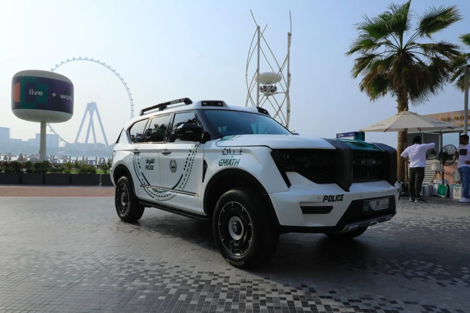 A white Dubai Police Ghiath patrol SUV parked on the JBR walk with the Ain Dubai wheel behind