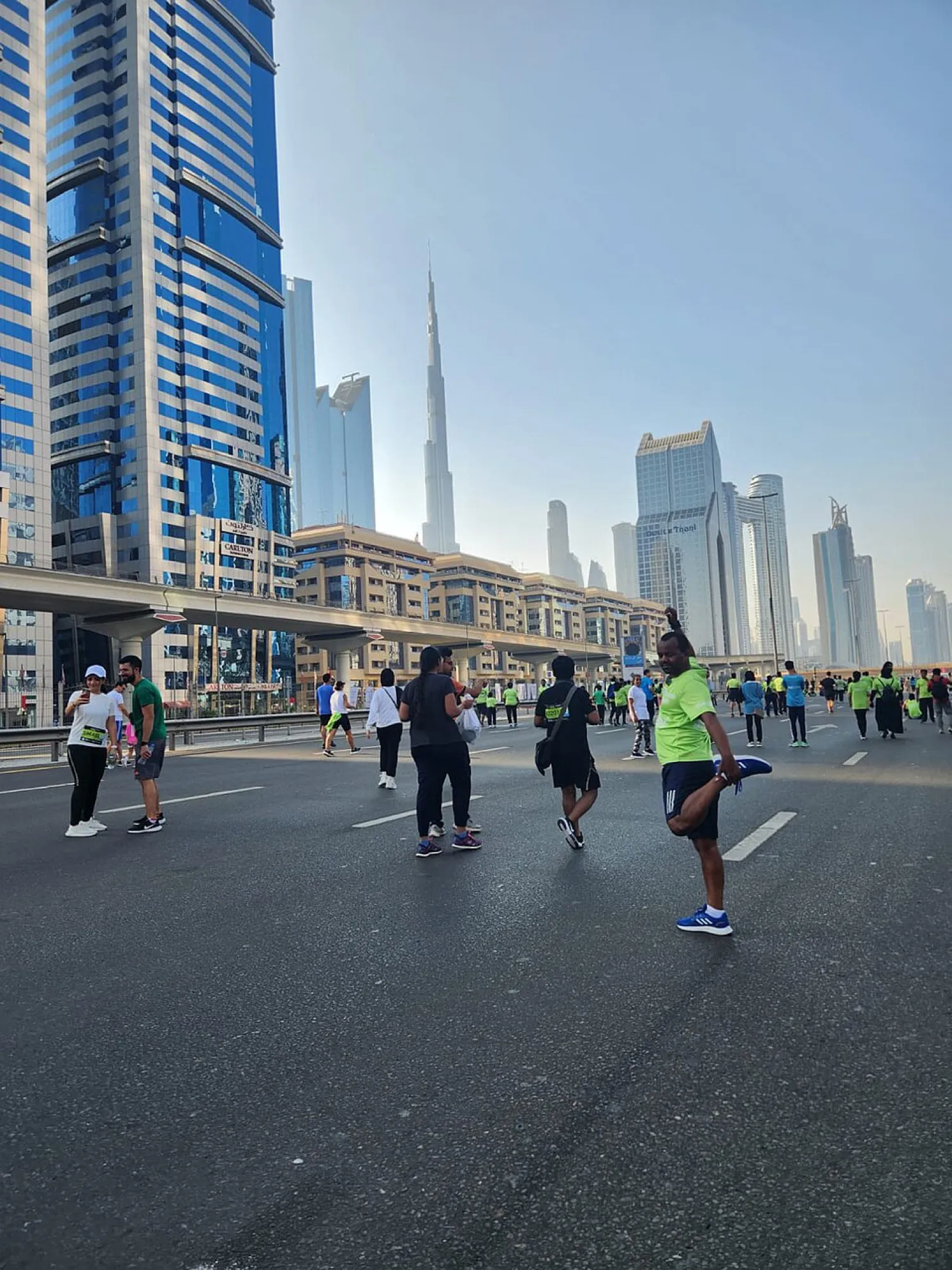 Dubai Run participants walking and stretching on a closed Sheikh Zayed Road, with Burj Khalifa in the distance