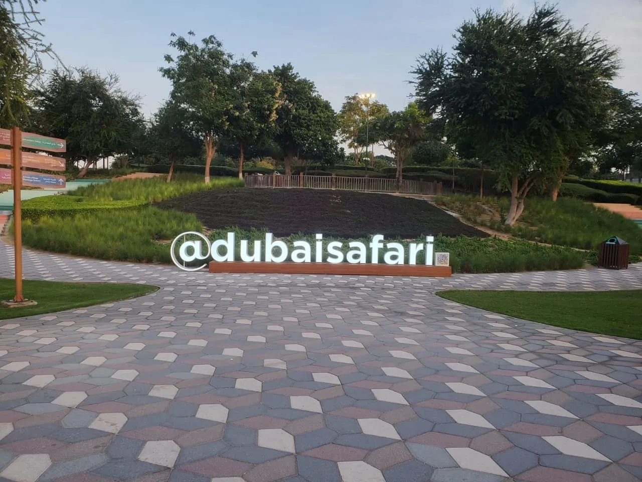 The Dubai Safari sign on the paved walkway inside the park's main entrance