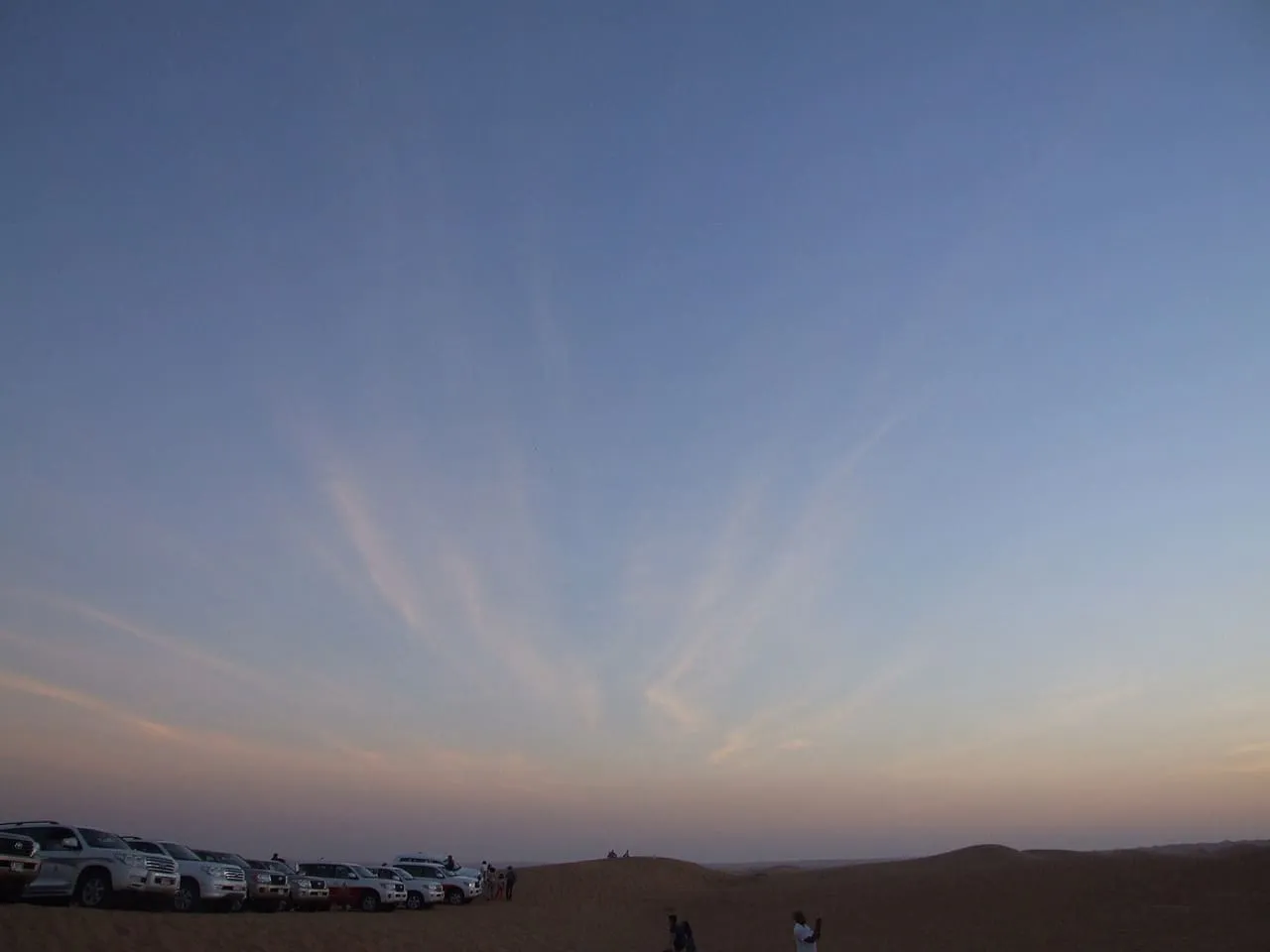 Safari 4x4s parked along a dune ridge under the evening sky in the Dubai desert