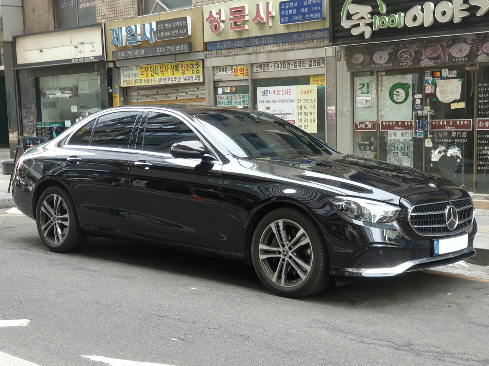 A black Mercedes-Benz E-Class sedan parked at the kerb, seen from the front right