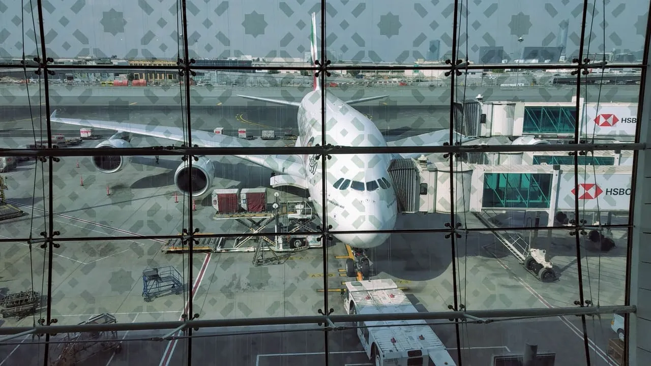 An Emirates Airbus A380 at a gate at Dubai International, seen through the patterned glass of the terminal