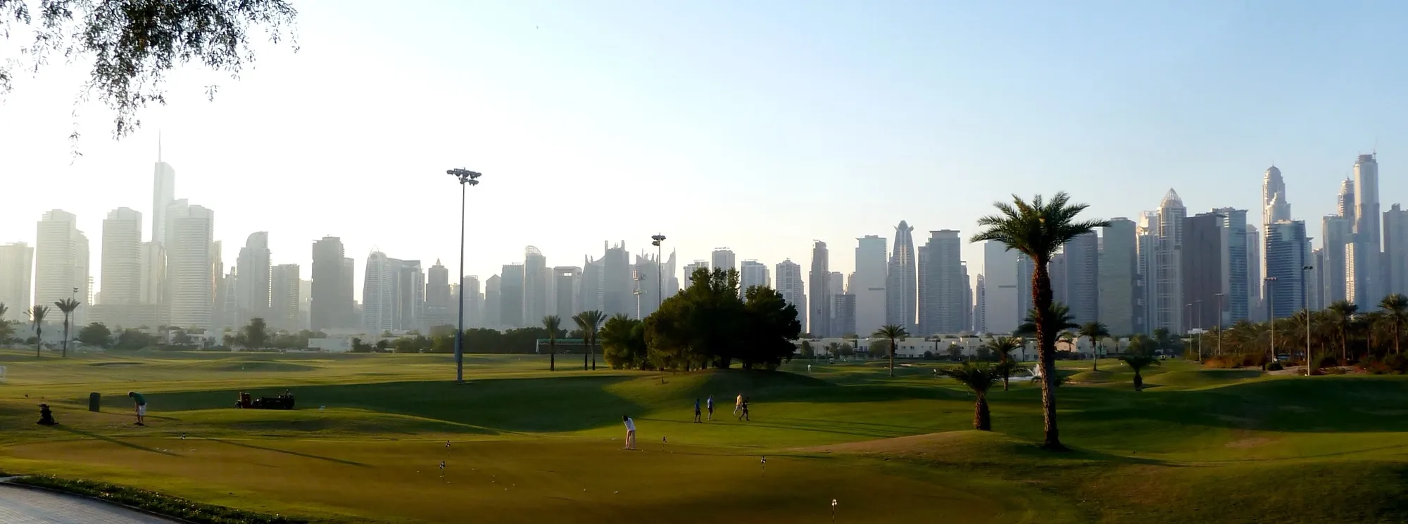 A golf course in Emirates Hills, Dubai, with the Jumeirah Lakes Towers and Dubai Marina skyline behind