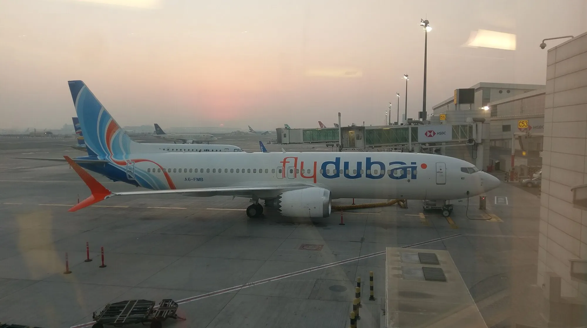 A flydubai Boeing 737 MAX at a gate at Dubai International Airport at dusk