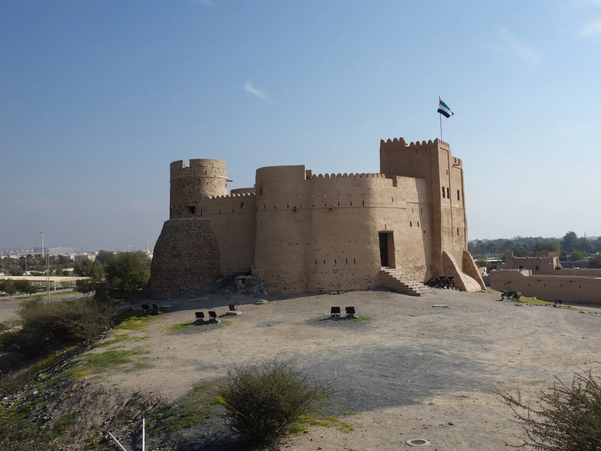 Fujairah Fort with its round towers and crenellated walls, flying the UAE flag