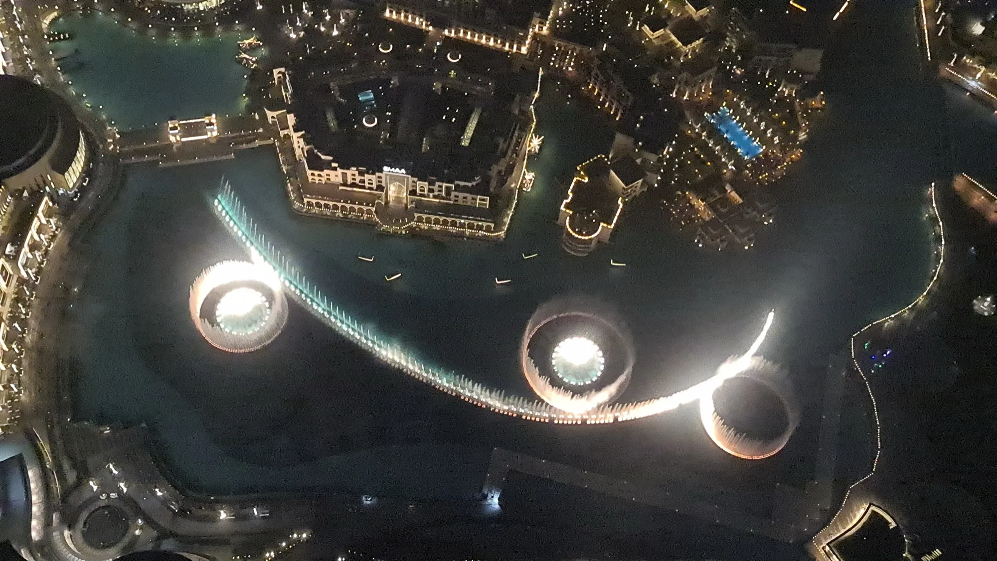 The Dubai Fountain lit up at night, seen from above beside the mall