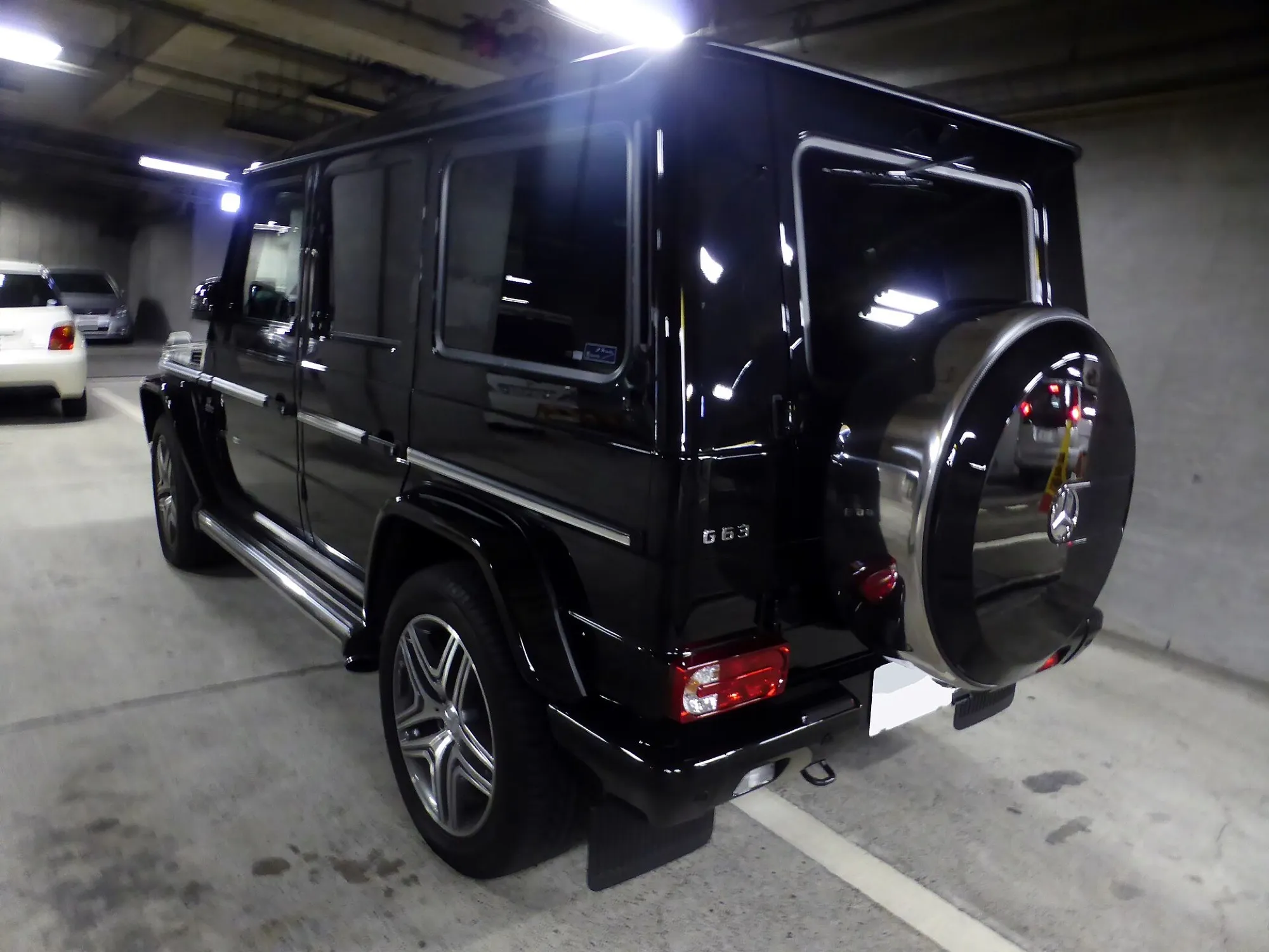 The rear of a black Mercedes-Benz G 63 AMG showing the side-hinged tailgate and spare wheel cover