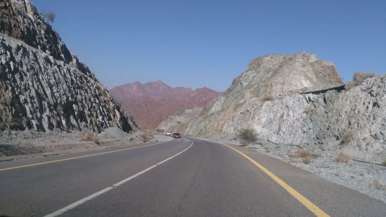 A road cutting through the rocky Hajar Mountains on the drive from Dibba towards Dubai