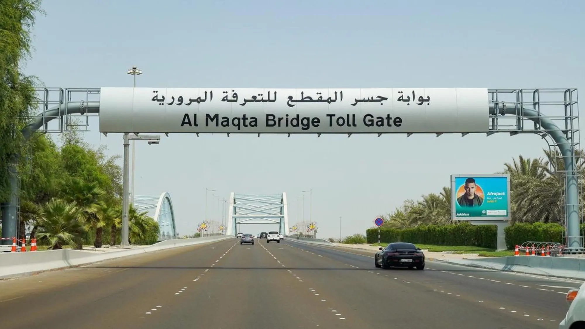 A toll gate gantry reading Al Maqta Bridge Toll Gate over an Abu Dhabi road, with the bridge arches beyond