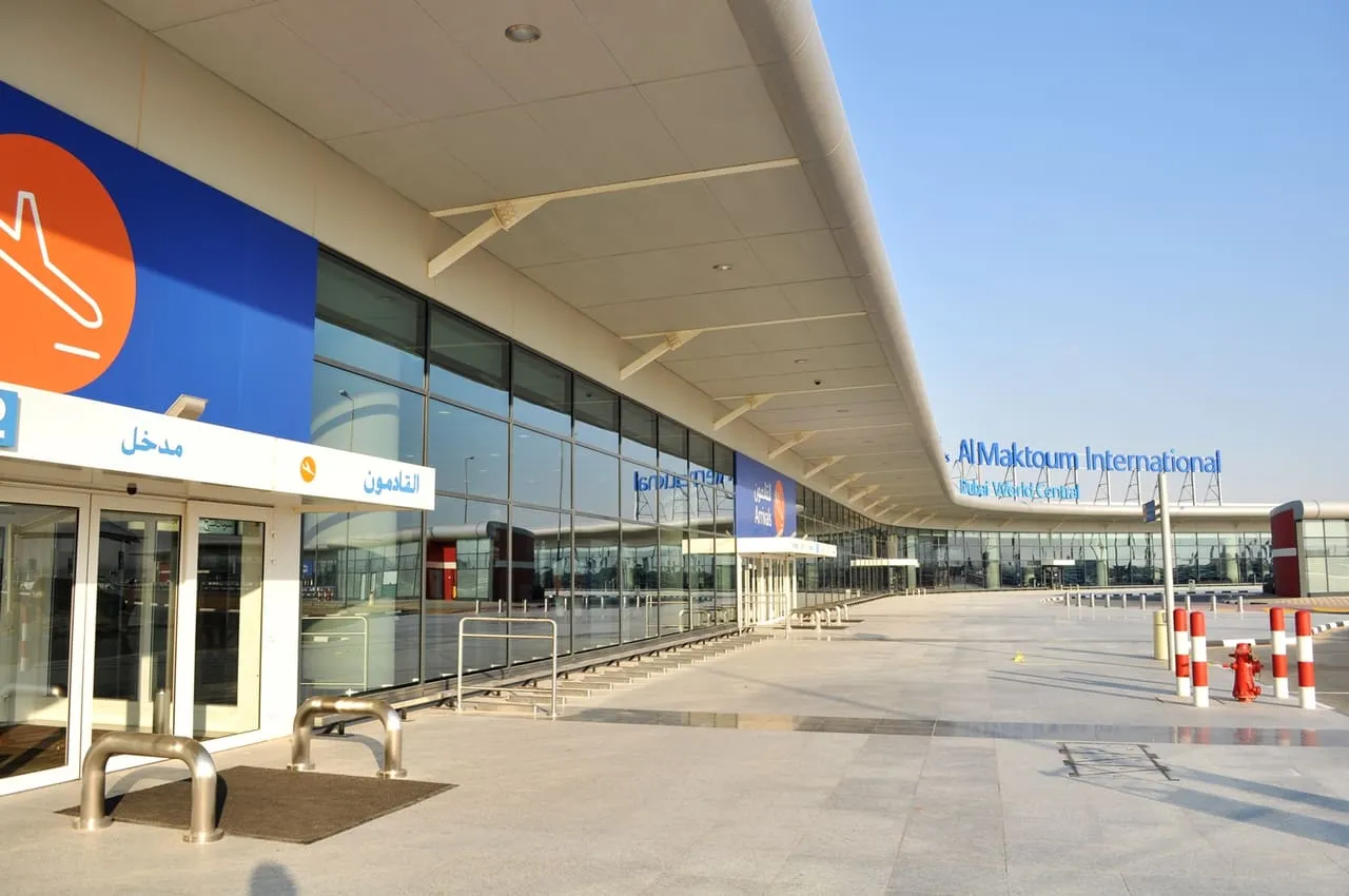 The arrivals entrance of the Al Maktoum International passenger terminal at Dubai World Central, with the airport name on the canopy