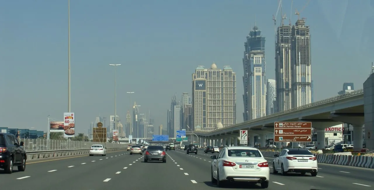 Cars on Sheikh Zayed Road in Dubai, heading towards the towers along the highway