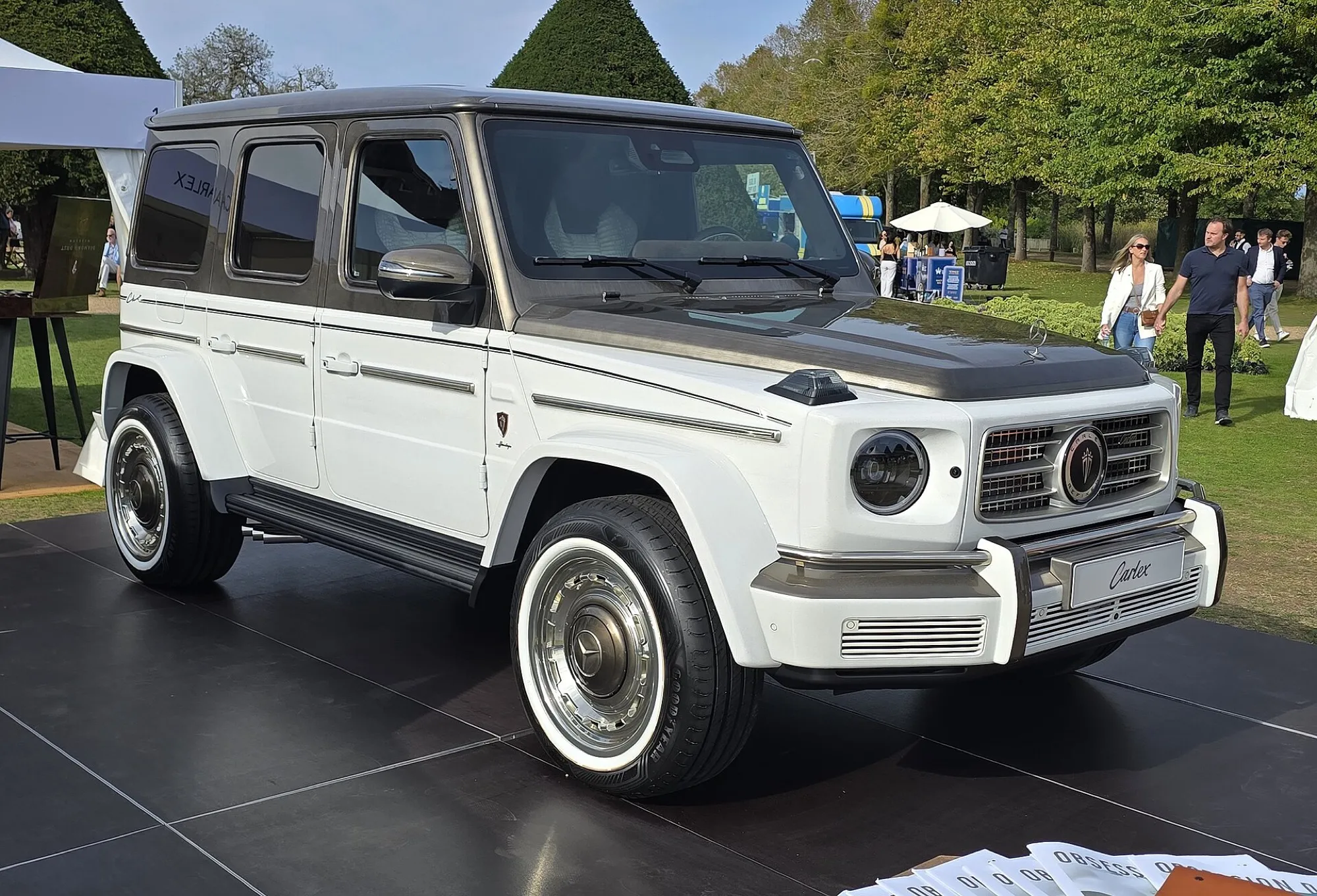 A white Mercedes-Benz G-Class (G 63 AMG) with chrome wheels, seen from the front three-quarter