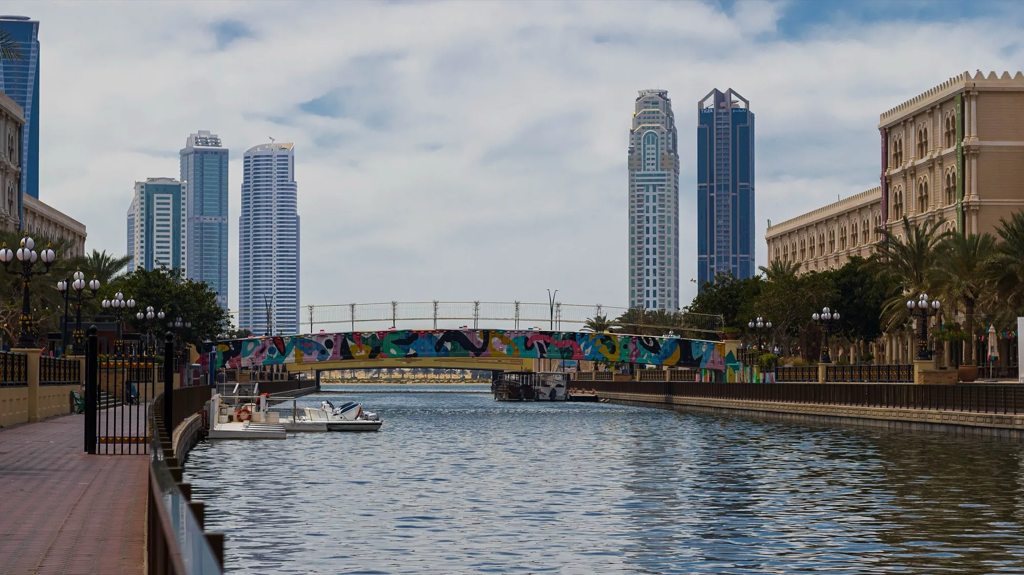 The Al Qasba canal in Sharjah with a painted footbridge and towers on either side