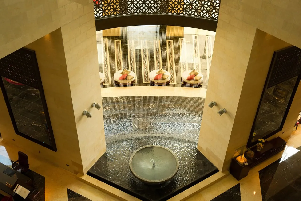 Atrium of a Dubai hotel with a stone fountain, water curtain and carved screens