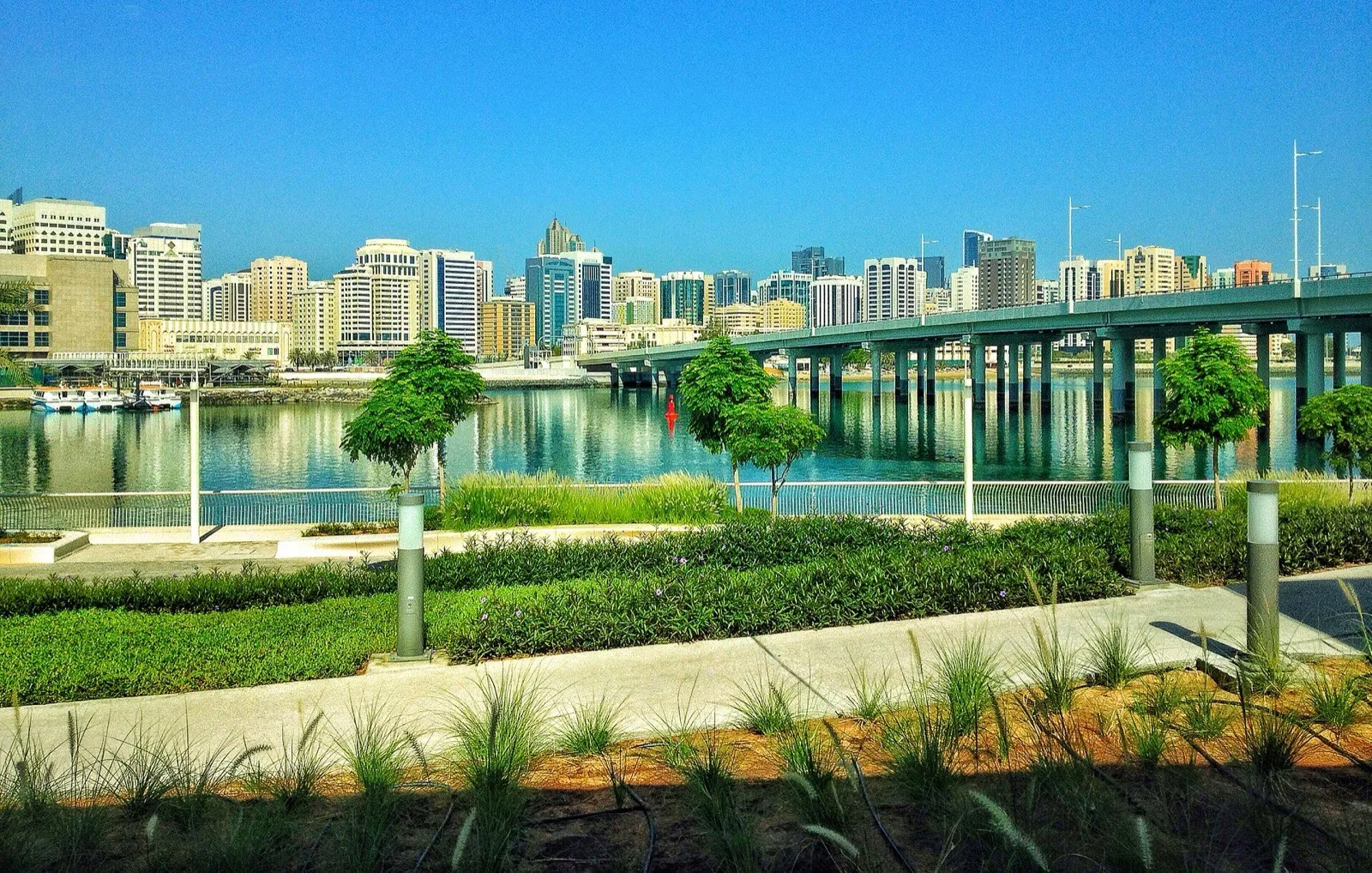 Abu Dhabi city buildings across the water from Al Maryah Island, with a road bridge on the right