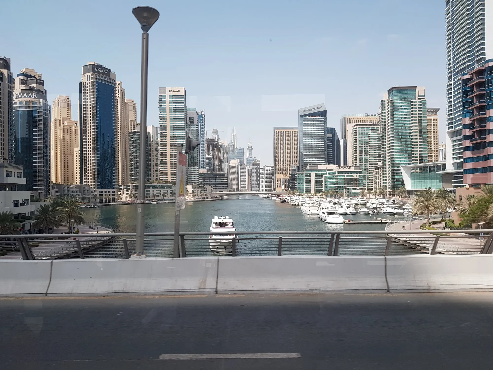 Dubai Marina canal with yachts and towers under a clear summer sky