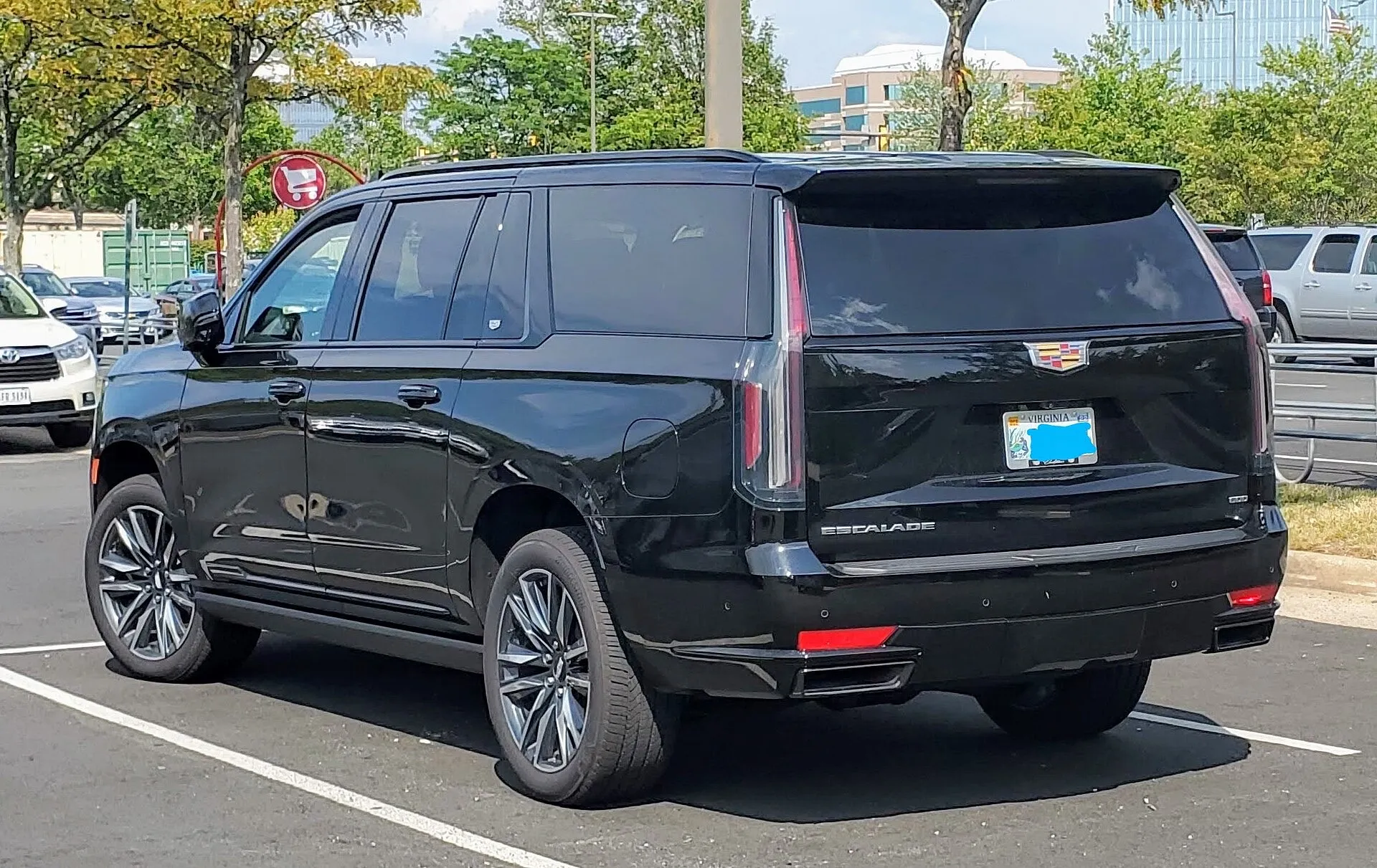 A black Cadillac Escalade full-size SUV seen from the rear and side in a car park