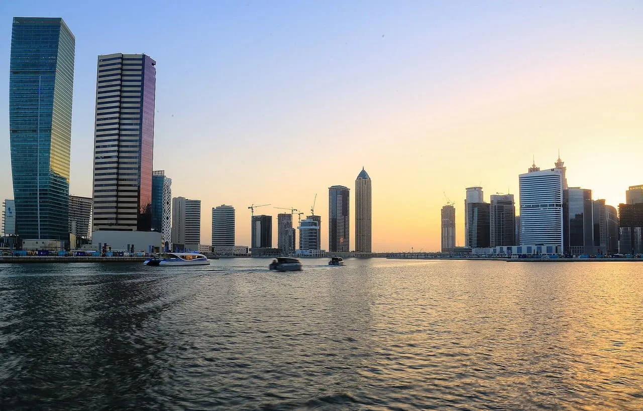 Boats on the Dubai Water Canal at sunset, with the Business Bay towers on both banks