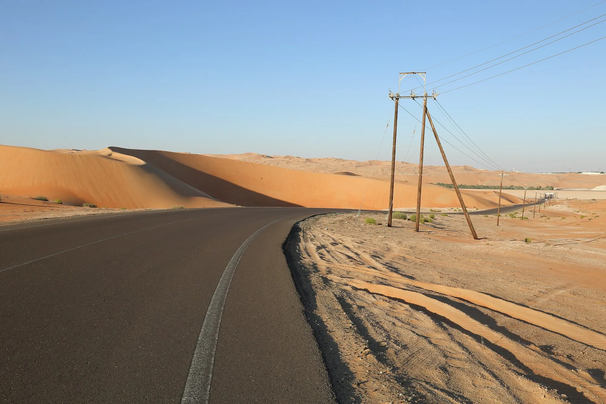 A paved road curving beside large orange sand dunes near Liwa in Abu Dhabi