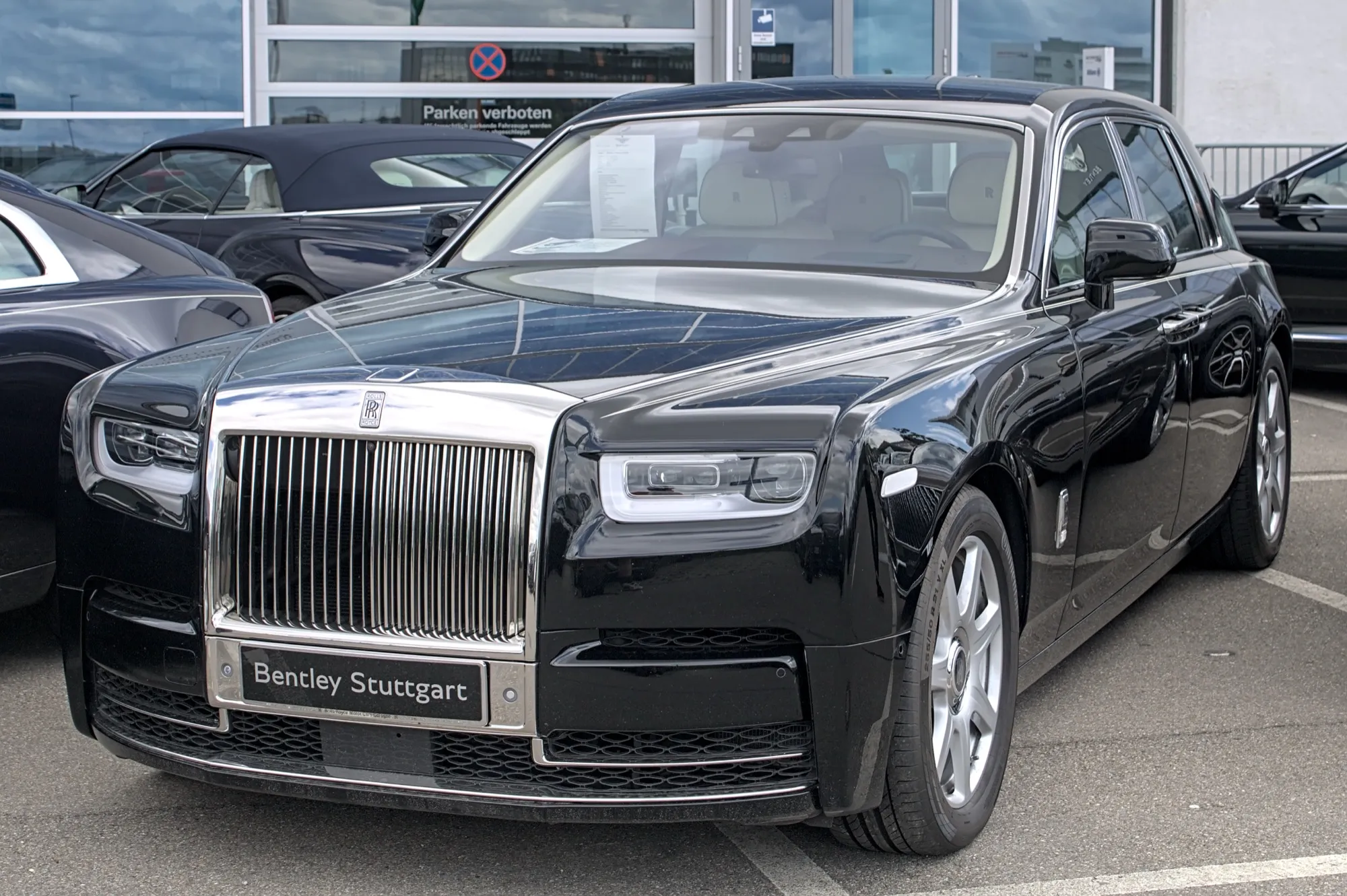 A black Rolls-Royce Phantom saloon seen from the front, parked outside a showroom