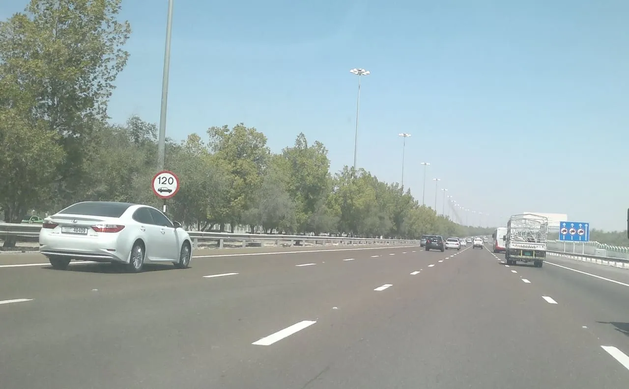 The tree-lined motorway from Abu Dhabi towards Dubai, with a 120 km/h speed limit sign