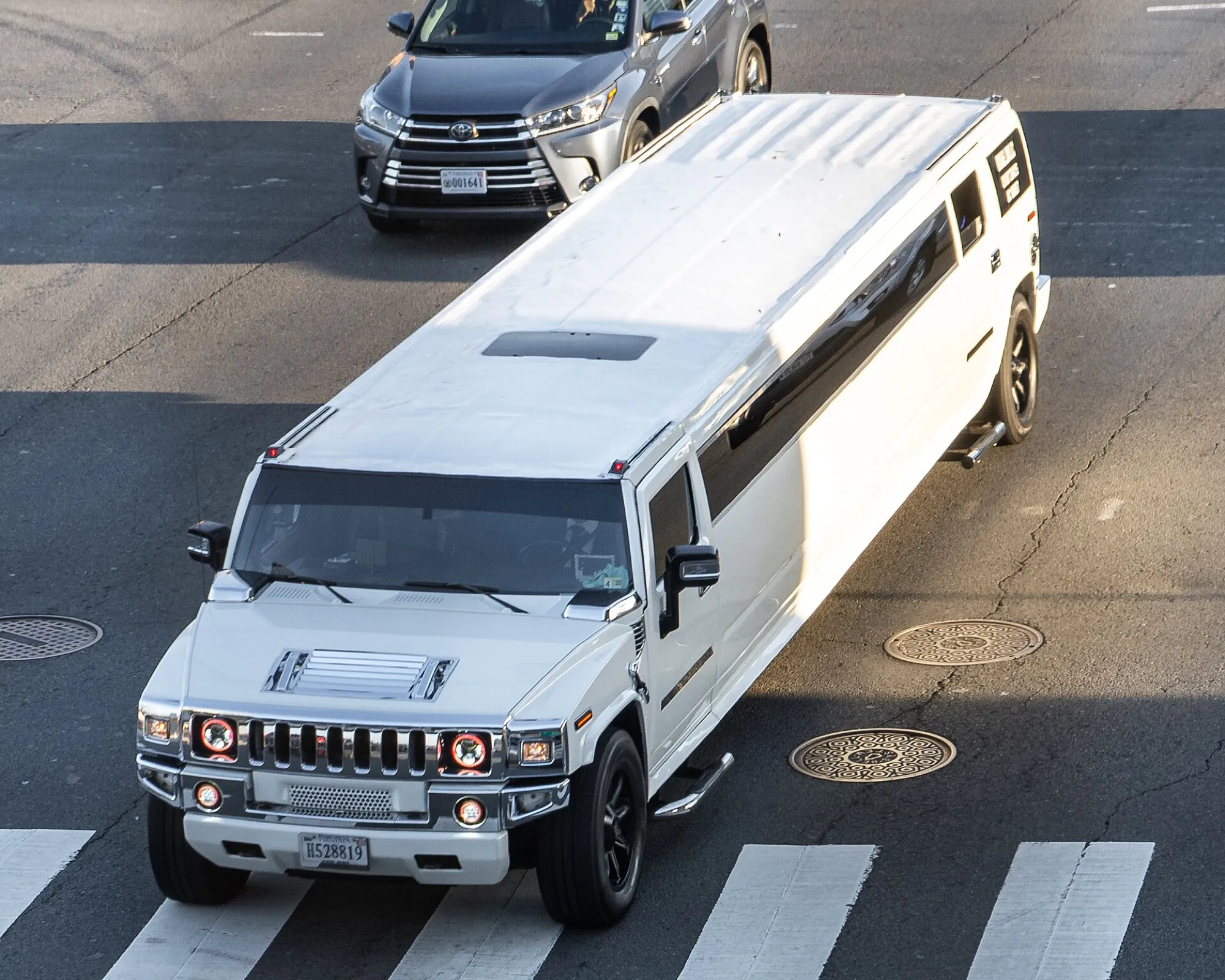 A white Hummer H2 stretch limousine seen from above at a junction