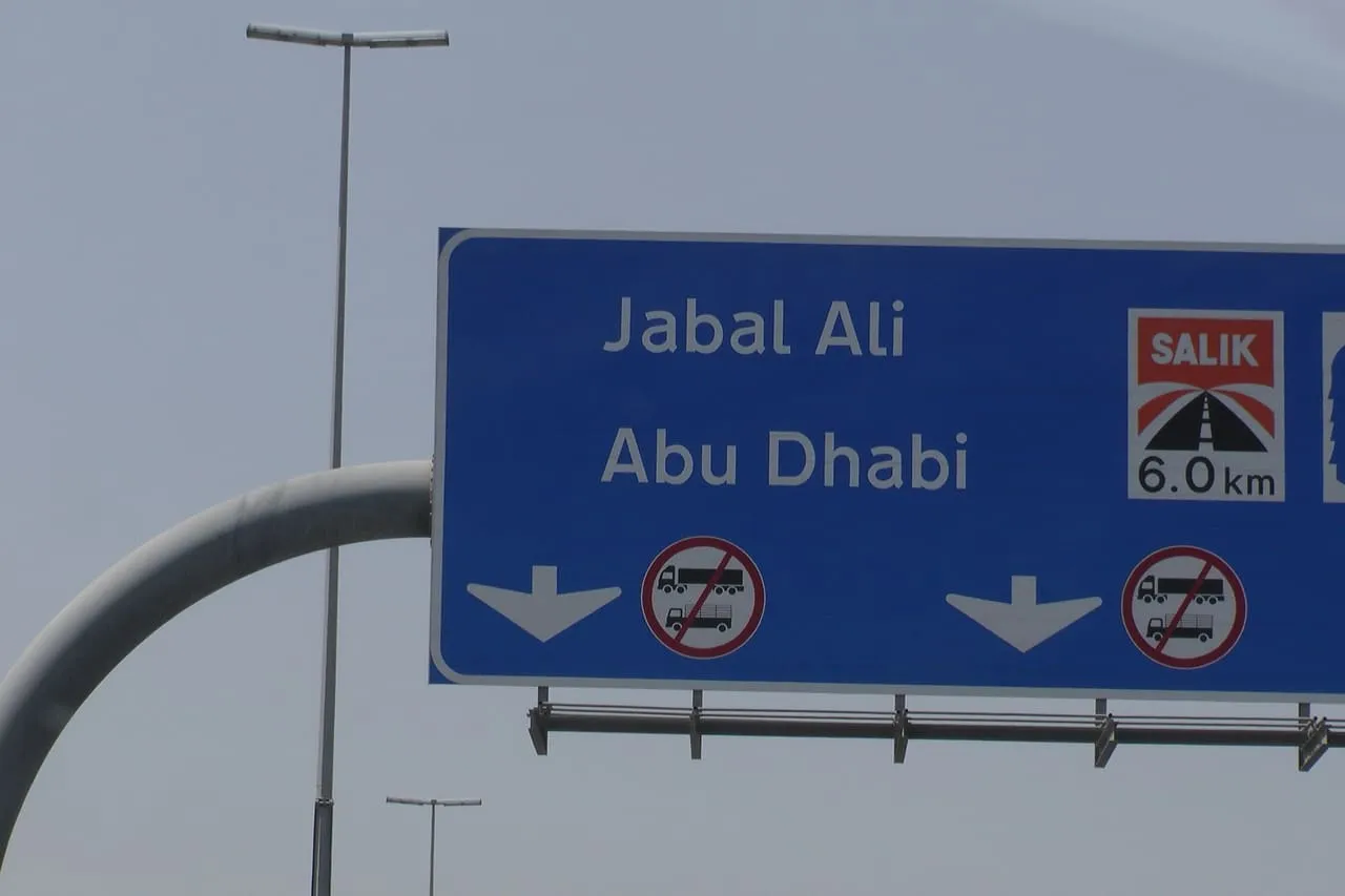 Overhead road sign in Dubai for Jabal Ali and Abu Dhabi, marking a Salik toll gate 6 km ahead