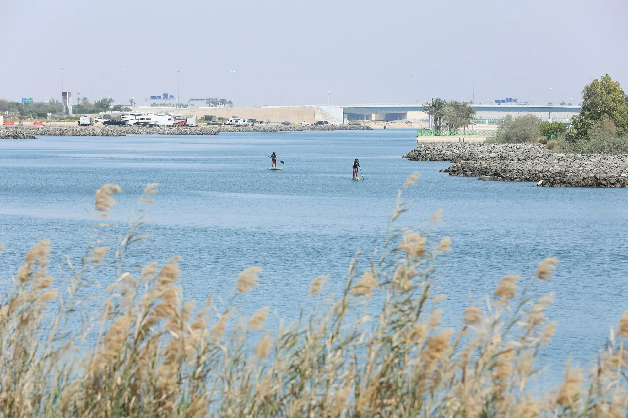 A waterway on Yas Island, Abu Dhabi, with paddleboarders and the shoreline beyond