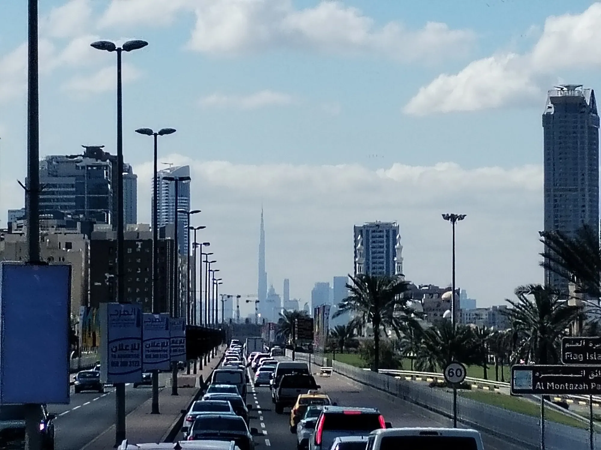 Slow traffic on a road in Sharjah, with the Burj Khalifa visible on the Dubai skyline