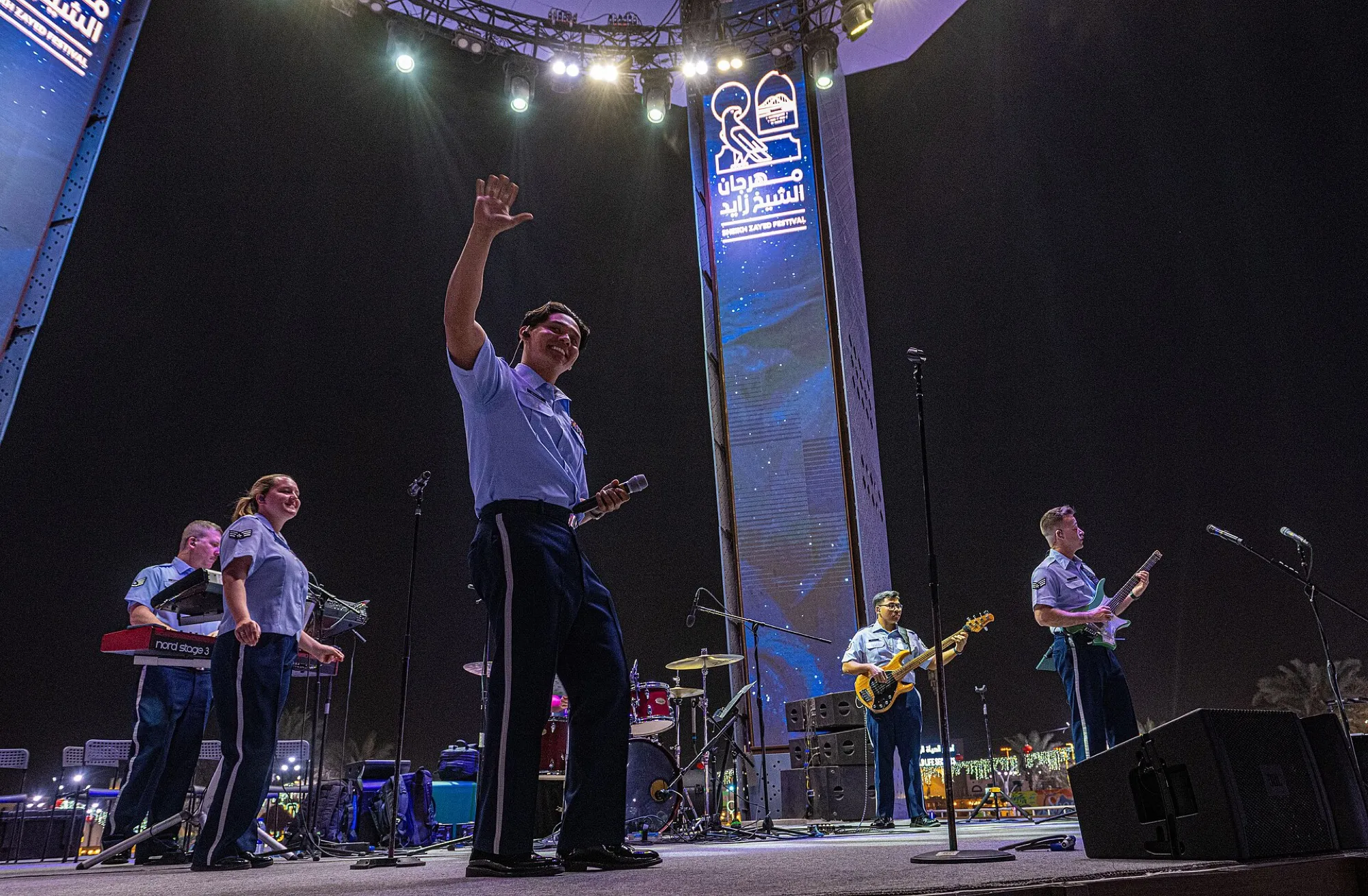 A band on the main stage at the Sheikh Zayed Festival at night, with the festival logo on a lit tower behind