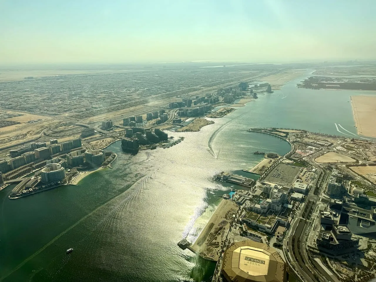 Aerial view of Yas Bay Waterfront on Yas Island, with the gold roof of Etihad Arena in the foreground