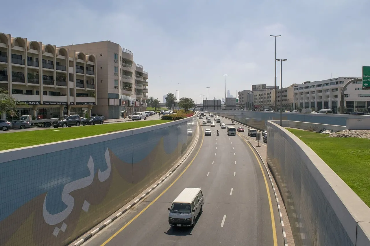 Traffic on Umm Hurair Road near Oud Metha in Dubai, with the Arabic word for Dubai tiled along the underpass wall